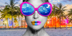 All I See surrealistic photographic artwork by Alexander Nicholas featuring a monochrome portrait wearing vibrant pink sunglasses reflecting an ocean scene against a colorful tropical backdrop, symbolizing perception, perspective, and emotion.
Person wearing colorful sunglasses with a beach and palm trees in the background