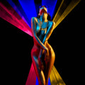 Night Life is a surrealistic photographic artwork by Alexander Nicholas exploring South Beach nightlife, music, energy, movement, freedom, and the pulse of South Beach after dark.
A stylized fashion portrait of a nude woman with her head tilted back, wearing a gold necklace and sunglasses, set against a black background with dramatic blue, pink, and gold light beams.